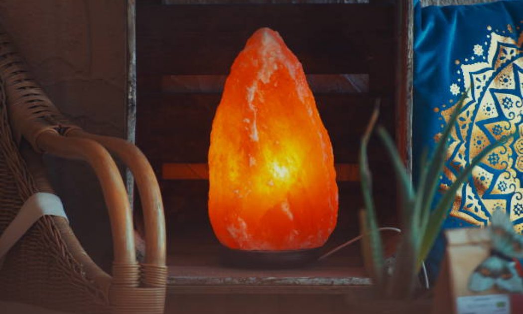 Himalayan salt lamp on wooden table illuminated